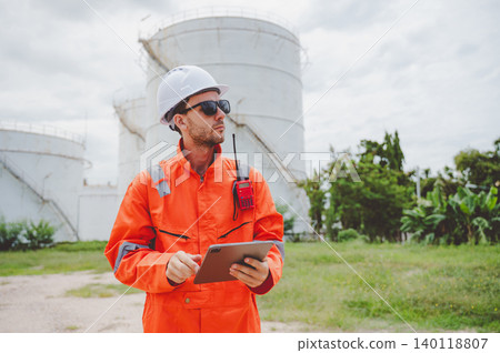 Field engineer inspecting data on a tablet at oil storage tanks Field engineer inspecting data on a tablet at oil storage tanks 140118807