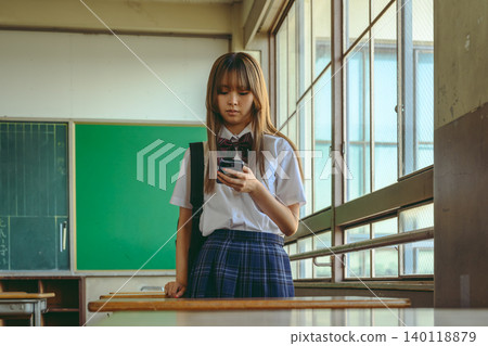 一名高中女生在教室裡看著她的智慧型手機。 一名高中女生在教室裡看著她的智慧型手機。 140118879