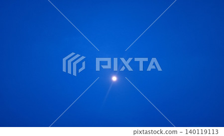 Real photograph of the moon shining in a deep blue evening sky with a calm minimalist atmosphere. 140119113