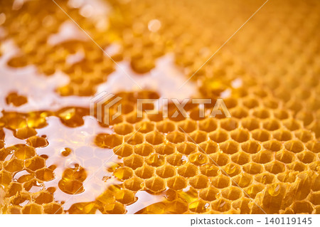 Macro shot of honey drop dripping from the honeycomb. A macro shot viscous honey, Macro shot of honey drop dripping from the honeycomb. A macro shot viscous honey, 140119145