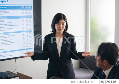 一群商務人士一邊看著螢幕一邊交談。 一群商務人士一邊看著螢幕一邊交談。 140120436