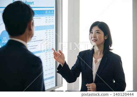 一群商務人士一邊看著螢幕一邊交談。 一群商務人士一邊看著螢幕一邊交談。 140120444