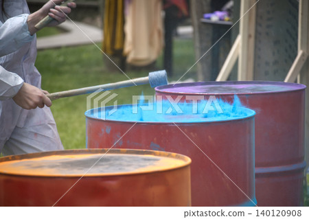 Person in protective suit mixing vibrant blue powder in large metal drums Person in protective suit mixing vibrant blue powder in large metal drums 140120908