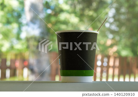 Disposable coffee cup with a stirrer on a table outdoors Disposable coffee cup with a stirrer on a table outdoors 140120910