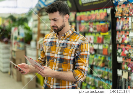 Adult man selects packets of seeds at gardening supermarket Adult man selects packets of seeds at gardening supermarket 140121384
