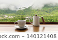 Coffee cup and drip pot on wooden table with foggy mountain background. 140121408