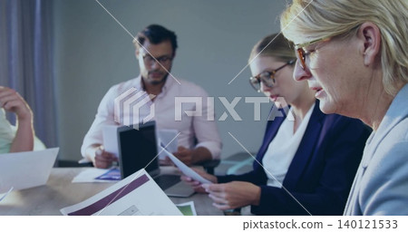 Reading woman in light blazer and glasses studying papers at meeting table with tablet, copy space Reading woman in light blazer and glasses studying papers at meeting table with tablet, copy space 140121533