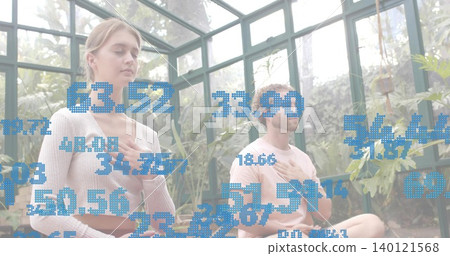 Meditating woman sitting on yoga mat in glass greenhouse, wearing pastel, blue data overlay Meditating woman sitting on yoga mat in glass greenhouse, wearing pastel, blue data overlay 140121568