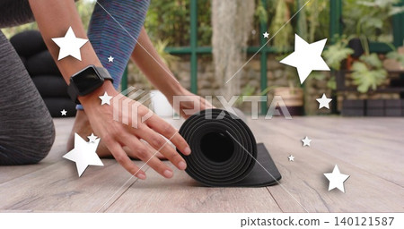Rolling hands and forearms guiding black yoga mat on wooden deck, showing smartwatch and leggings Rolling hands and forearms guiding black yoga mat on wooden deck, showing smartwatch and leggings 140121587