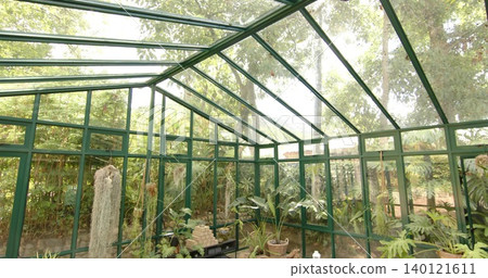 Filling greenhouse interior with green metal frame and potted plants, black bench holding bricks 140121611