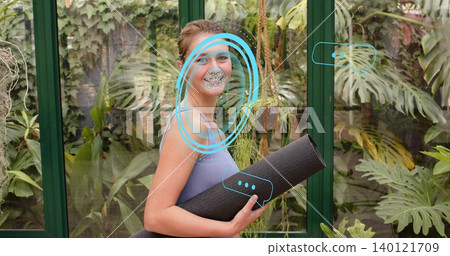 Holding rolled black yoga mat, woman in light purple tank standing in greenhouse with blue overlays Holding rolled black yoga mat, woman in light purple tank standing in greenhouse with blue overlays 140121709