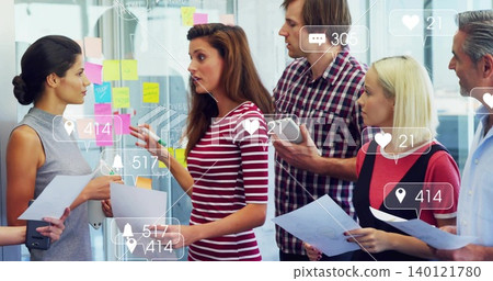 Leading woman in red-and-white top presenting at glass wall with notes, papers, phone, social icons Leading woman in red-and-white top presenting at glass wall with notes, papers, phone, social icons 140121780