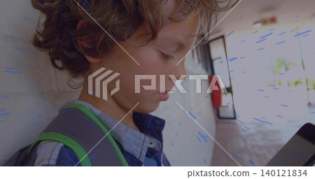 Leaning boy checking handheld device in breezeway, blue plaid shirt, backpack strap, copy space Leaning boy checking handheld device in breezeway, blue plaid shirt, backpack strap, copy space 140121834