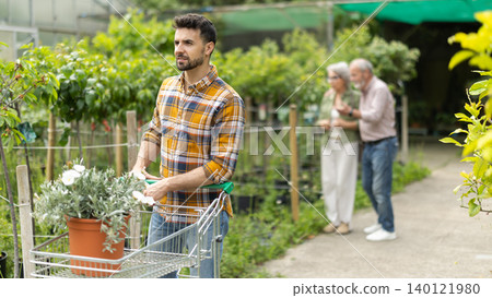 Adult man choose tree seedlings in garden supermarket Adult man choose tree seedlings in garden supermarket 140121980