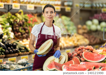Adult woman seller putting melon in vegetable shop 140121990