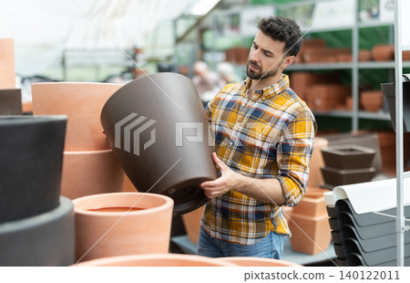 Adult man choose clay flower pots together at market Adult man choose clay flower pots together at market 140122011