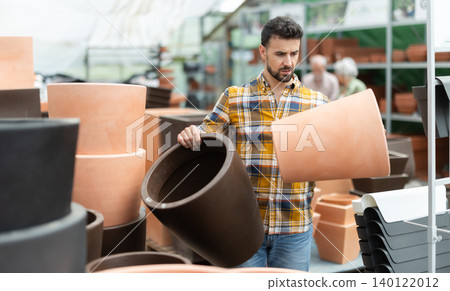 Man chooses large flower pot-tub in shop Man chooses large flower pot-tub in shop 140122012