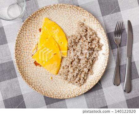 Boiled pearl barley with omelette served on dish on checkered cloth Boiled pearl barley with omelette served on dish on checkered cloth 140122020