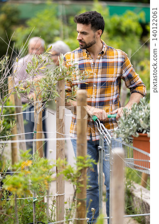 Adult man choosing tree seedlings in pots at flower shop 140122061