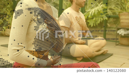 Practicing couple meditating on yoga mats in plant studio, cream sweater, red pants, dotted overlay Practicing couple meditating on yoga mats in plant studio, cream sweater, red pants, dotted overlay 140122080