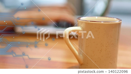 Sitting speckled beige ceramic mug on wood table, blurred laptop hands and blue circuit, copy space Sitting speckled beige ceramic mug on wood table, blurred laptop hands and blue circuit, copy space 140122096