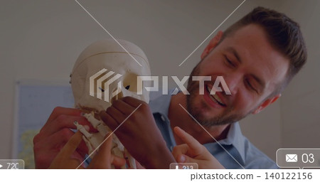 Smiling teacher in blue shirt holding skull, showing features in class, hands and jaw, copy space Smiling teacher in blue shirt holding skull, showing features in class, hands and jaw, copy space 140122156
