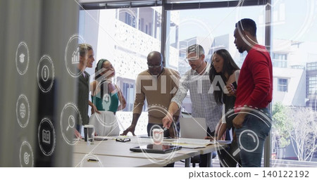 Discussing six team members wearing business casual at meeting table, viewing laptop, AR icons 140122192