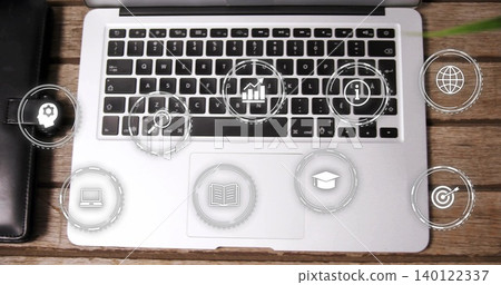 Displaying silver laptop centered on wood desk, black keys and trackpad showing HUD icons, folio Displaying silver laptop centered on wood desk, black keys and trackpad showing HUD icons, folio 140122337