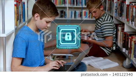 Typing left boy in blue-tshirt using laptop in school library aisle, padlock-hologram, copy space Typing left boy in blue-tshirt using laptop in school library aisle, padlock-hologram, copy space 140122340