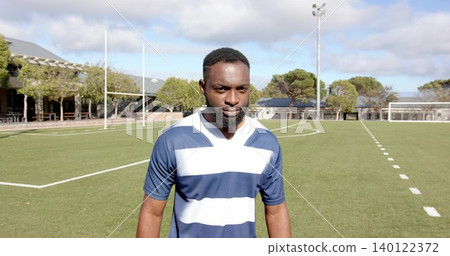 Standing adult male wearing navy-striped jersey on turf field with lines, goalposts, light pole Standing adult male wearing navy-striped jersey on turf field with lines, goalposts, light pole 140122372
