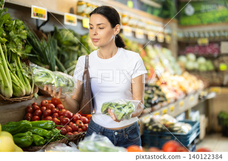 Focused positive woman shopping in organic food store, choosing beans Focused positive woman shopping in organic food store, choosing beans 140122384