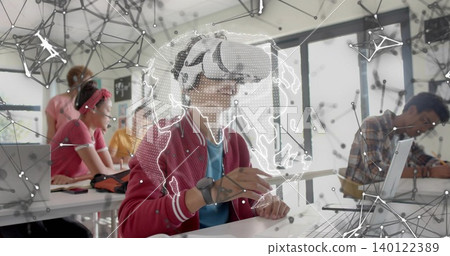 Exploring red-jacketed teenager with VR headset holding stylus in class, with AR globe and laptops Exploring red-jacketed teenager with VR headset holding stylus in class, with AR globe and laptops 140122389