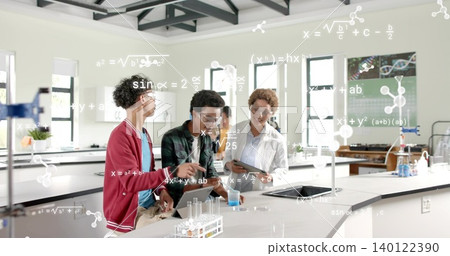 Guiding teacher in lab coat and goggles showing students pouring blue liquid into beakers at school Guiding teacher in lab coat and goggles showing students pouring blue liquid into beakers at school 140122390