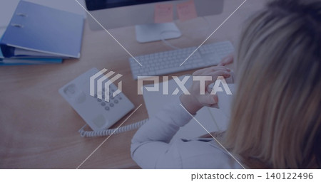 Holding handset, woman wearing light blazer talking on corded phone at office desk, copy space Holding handset, woman wearing light blazer talking on corded phone at office desk, copy space 140122496