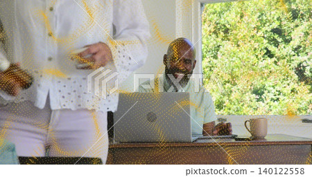 Typing man using laptop at home, mug and smartphone, senior woman in white blouse walking Typing man using laptop at home, mug and smartphone, senior woman in white blouse walking 140122558