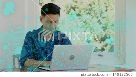 Typing adult Asian man in blue shirt using laptop at desk by window, with turquoise overlay Typing adult Asian man in blue shirt using laptop at desk by window, with turquoise overlay 140122563