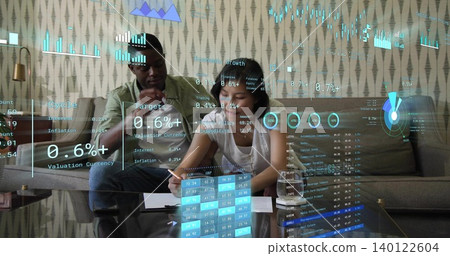 Analyzing couple sitting on sofa at home, man in mint shirt, woman writing, financial overlays Analyzing couple sitting on sofa at home, man in mint shirt, woman writing, financial overlays 140122604