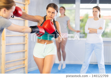 Women in boxing gloves punch deliver blow each other during training sparring session Women in boxing gloves punch deliver blow each other during training sparring session 140122709