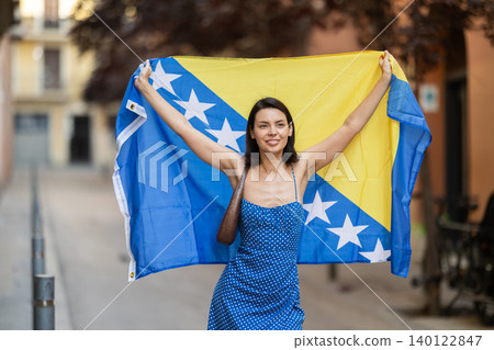 Young woman with flag of Bosnia and Herzegovina on city street 140122847