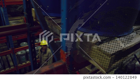 Inspecting worker wearing yellow hard hat, khaki vest scanning racks in storage, drums, copy space Inspecting worker wearing yellow hard hat, khaki vest scanning racks in storage, drums, copy space 140122849