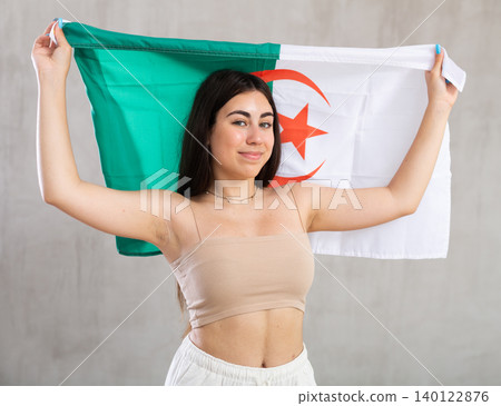 Young woman with flag of Algeria posing in studio 140122876