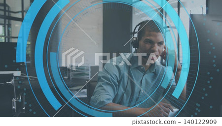 Speaking support agent wearing blue shirt typing on keys at office desk with headset, monitors, HUD Speaking support agent wearing blue shirt typing on keys at office desk with headset, monitors, HUD 140122909