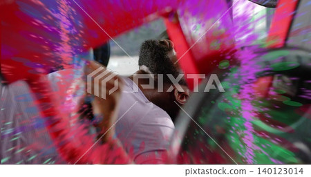 Leaning man in white T-shirt tilting head back in red cabin, paint splatters, wheel, blurred hand Leaning man in white T-shirt tilting head back in red cabin, paint splatters, wheel, blurred hand 140123014