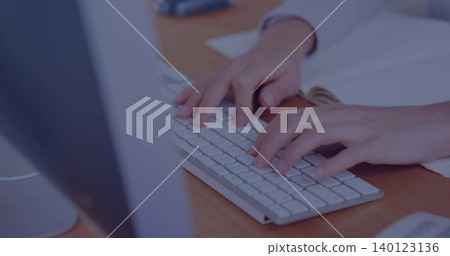 Typing woman wearing white cuff at office desk, using slim white keyboard, papers, silver monitor Typing woman wearing white cuff at office desk, using slim white keyboard, papers, silver monitor 140123136