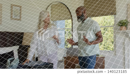 Packing woman in white blouse filling open suitcase on bed in bedroom, man gesturing near dresser 140123185