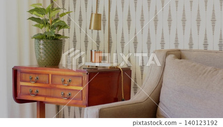 Wooden side table showing green planter, brass lamp, notebook with cable in lounge nook, copy space Wooden side table showing green planter, brass lamp, notebook with cable in lounge nook, copy space 140123192