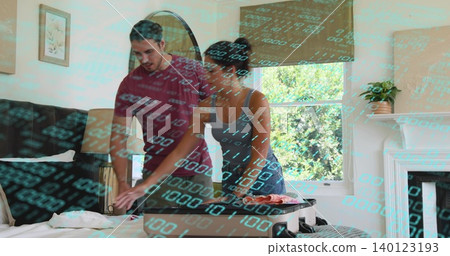 Packing couple leaning over bed at home, arranging clothes in open carry-on suitcase Packing couple leaning over bed at home, arranging clothes in open carry-on suitcase 140123193