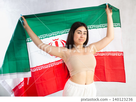 Happy young woman with flag of Iran against unicoloured background 140123236