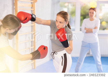 Teen girls in punch mitts boxing 140123302
