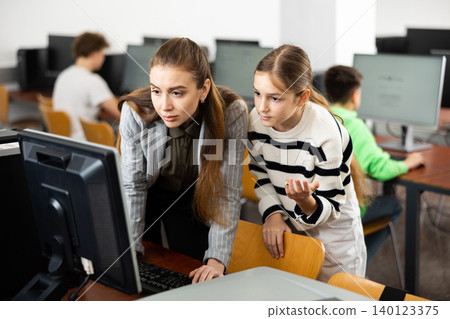 Female teacher and teenage girl looking at monitor of PC 140123375